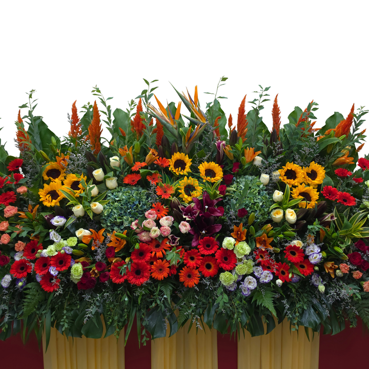 Close-up of the Prosperity Spire grand opening stand showing sunflowers, red gerbera, bird of paradise and orange celosia